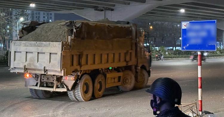 Một cảnh sát giao thông đang kiểm tra giấy tờ và trọng tải của một chiếc xe tải tại trạm cân di động